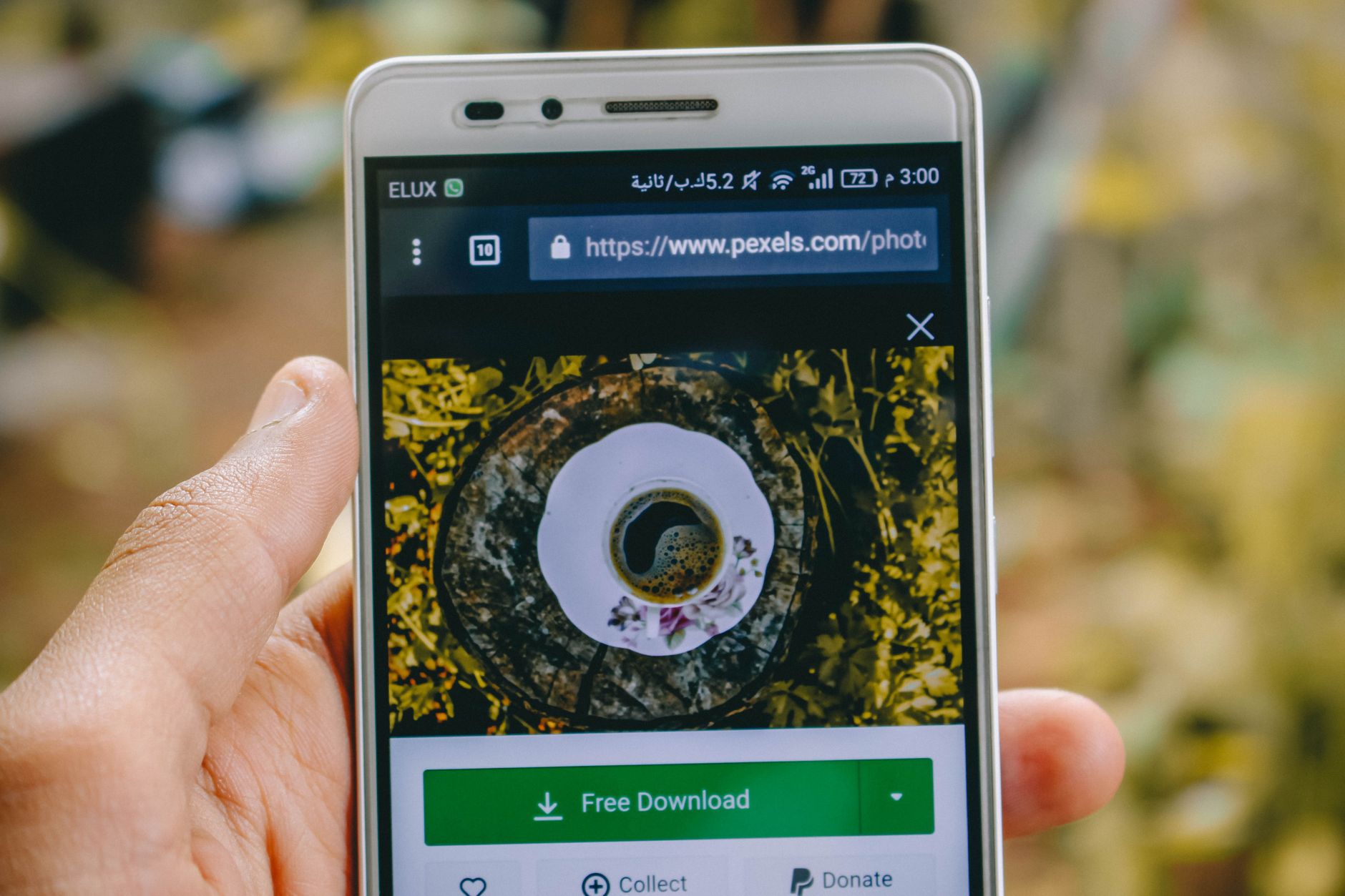 Close-up of a smartphone showing a coffee cup image on a screen outdoors.